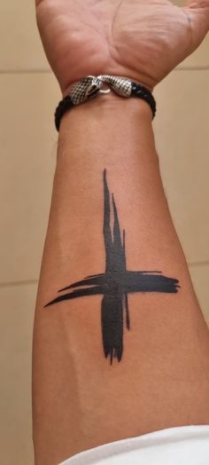 a person with a cross tattoo on their arm