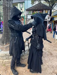 two people dressed up in costume standing next to each other near a tree and building