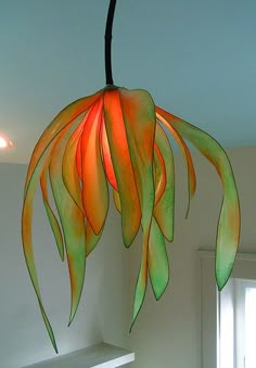 an orange and green flower hanging from a ceiling fixture in a room with white walls