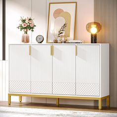 a white and gold sideboard with flowers on top in front of a wall mounted clock