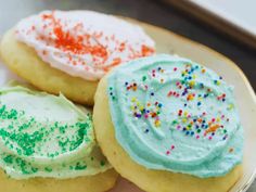 three decorated cookies on a plate with sprinkles and frosting in the middle