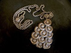 "This pendant of machine stamped feathery swirls of silver plated brass is attached to a pretty chain with details that complement the pendant. It is unsigned and I imagine it to be from before mid century, but I can't be sure. The quality is good as is the condition with just slight surface wear to the pendant. The necklace chain is 24\" long. The pendant is 2 1/2\" long X 1. 3/4\" wide." Silver Spiral Bohemian Necklace, Bohemian Silver Spiral Necklace, Puka Shell Necklace, Puka Shell, Butterfly Bracelet, Ring Photos, Shell Necklaces, Necklace Chain, Vintage Necklace