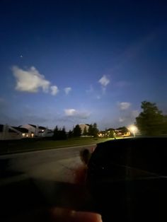 a person driving down the road at night with their hand on the car's windshield