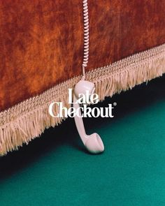 an old phone sitting on top of a green carpet next to a brown wall with the words late checkout