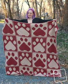 a woman is holding up a red and white blanket