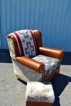 an old chair and ottoman are sitting on the ground in front of a blue building