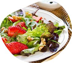 a white plate topped with a salad and strawberries