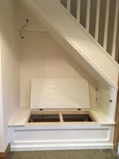 an under the stairs storage area in a house with white painted walls and wood flooring