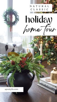 a black vase filled with greenery sitting on top of a table next to a christmas tree