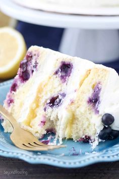 a slice of blueberry cake on a plate with a fork and lemon wedges