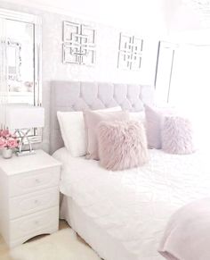 a white bed with pink pillows in a bedroom