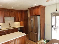 a kitchen with wooden cabinets and stainless steel refrigerator