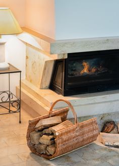 a basket sitting on the floor next to a fire place with logs in front of it