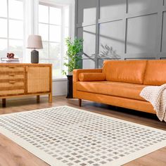 a living room with a brown couch and black and white rug