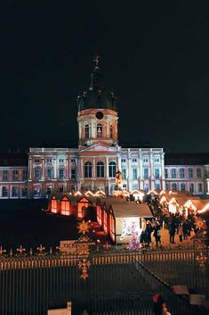 people are walking around in front of a large building with christmas lights on it's sides