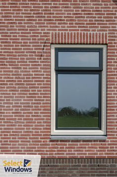 a red brick building with a large window on it's side and grass in the background