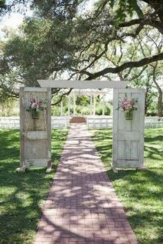 an outdoor wedding ceremony with white wooden doors and pink flowers