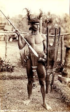 an old photo of a native american man holding a spear