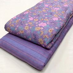 two purple bedspreads stacked on top of each other, one with floral print