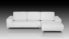 a white leather couch sitting on top of a white floor next to a black wall