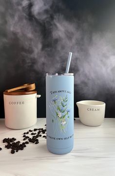 a cup with a straw in it sitting next to some coffee beans on a table