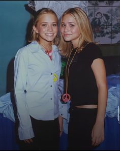 two young women standing next to each other in front of a wall with pictures on it