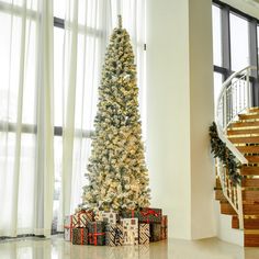 a decorated christmas tree sitting in front of a window next to a spiral stair case