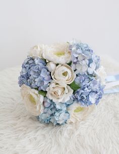 a bridal bouquet with blue and white flowers on a furnishing area in front of a white wall