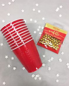 a red plastic cup next to a bag of gold flakes on a gray background