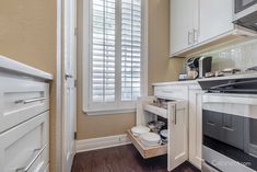 a kitchen with white cabinets and wooden floors