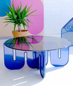 a glass table with blue legs and a potted plant on top