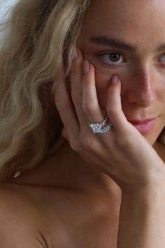 a close up of a person with a ring on their finger and her hand near her face