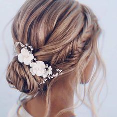 a woman with blonde hair and flowers in her hair is wearing a white flower clip