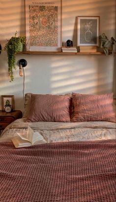 the bed is made up with pink sheets and pillows, along with pictures on the wall