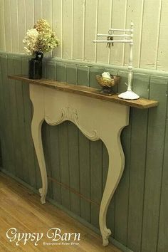 an old table is painted white and has some flowers on the shelf next to it