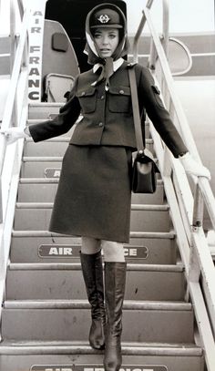 a woman in an air force uniform is standing on the stairs leading to an airplane