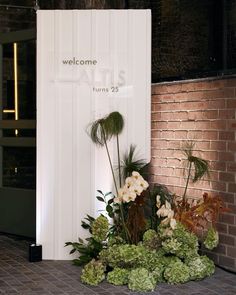 flowers and greenery are displayed in front of the entrance to an event venue that is open for business