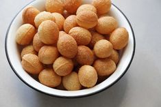 a white bowl filled with sugared donuts on top of a gray countertop