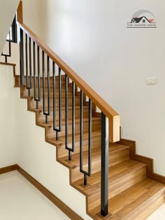 a wooden staircase with black railing and handrail