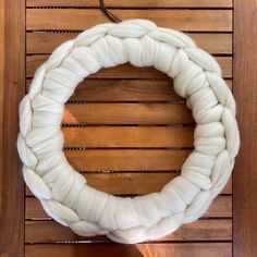 a white yarn wreath sitting on top of a wooden table