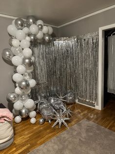 silver and white balloons are hanging from the ceiling