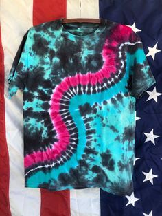 a tie - dyed t - shirt hanging on an american flag