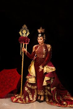 a woman in a red and gold dress holding an umbrella with her hand on it