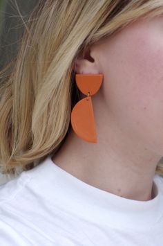 This is a pair of earrings in a beautiful, deep orange color- the shade is rich and flattering while the shapes are eye-catching and modern. They dangle comfortably on your ear and are sure to brighten up any outfit you choose. These earrings are crafted using polymer clay, a surprisingly lightweight material that won't weigh you down. Each earring is carefully sanded and smoothed to ensure a well-made piece of jewelry that is comfortable to wear. Components: polymer clay & hypo-allergenic s Bold Orange Drop Earrings, Trendy Orange Round Earrings, Orange Minimalist Earrings For Everyday, Minimalist Orange Earrings For Everyday, Modern Orange Earrings For Everyday Wear, Everyday Minimalist Orange Earrings, Minimalist Handmade Orange Earrings, Handmade Minimalist Orange Earrings, Orange Minimalist Dangle Jewelry