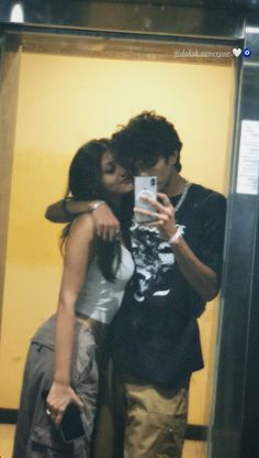 a man and woman taking a selfie in front of a mirror with their arms around each other