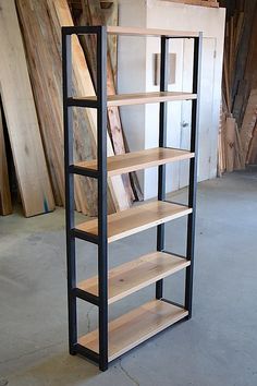 a book shelf made out of wood and black metal shelves in a room with unfinished boards