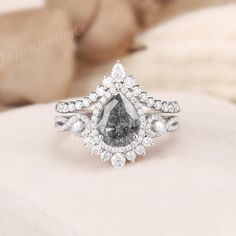 an engagement ring with a pear shaped gray diamond surrounded by smaller white diamonds on top