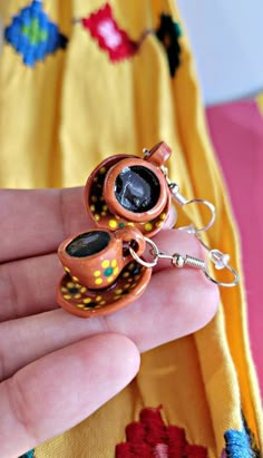 a hand holding a pair of earrings in it's left hand, with an owl design on the back