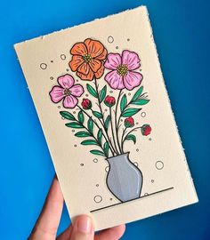 a hand holding a card with flowers in a vase