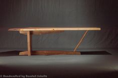 a wooden table sitting on top of a black surface in front of a gray background